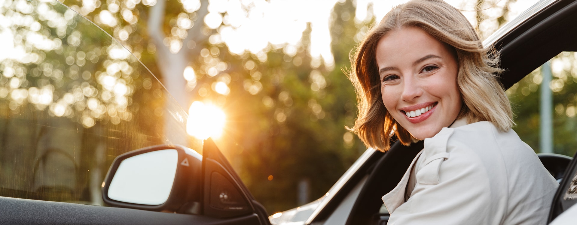 Eine lächelnde Frau steigt aus Ihrem Auto aus