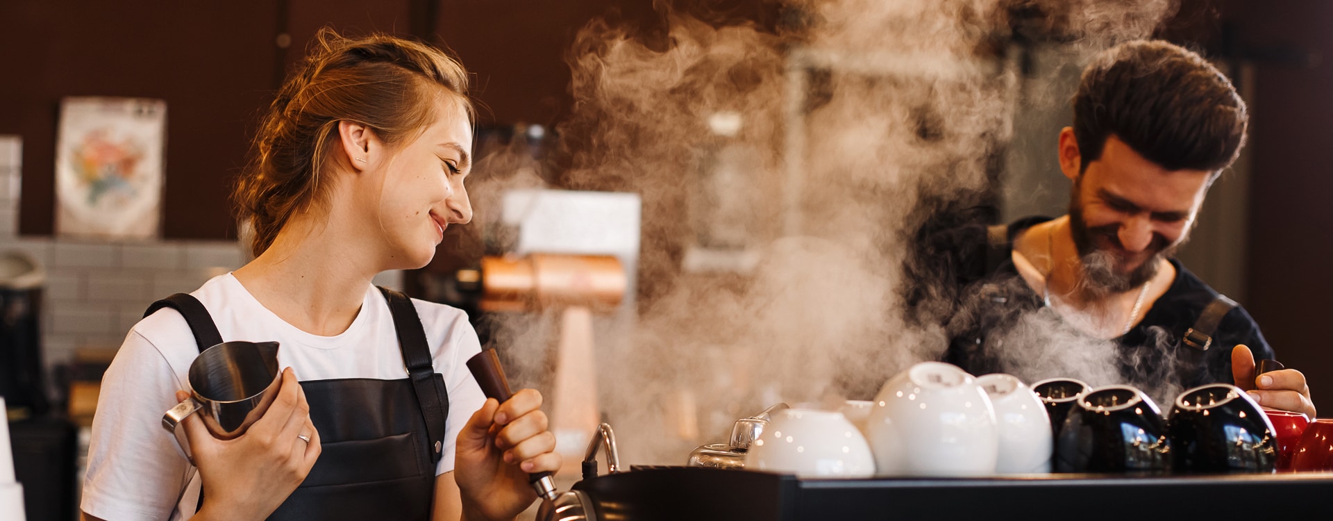 Personen kochen Kaffe an einer dampfenden Kaffeemaschine in einem Restaurant